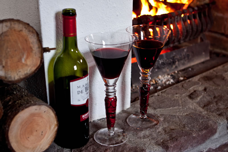 Open turf fire and hearthside with bottle of red wine and two glasses