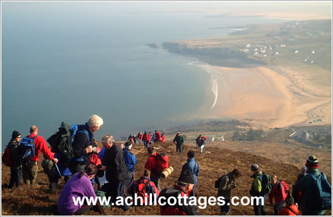 Walkers rest on the slopes of Slievemore mountain, overlooking the Golden Strand beach at Dugort, Achill Island